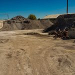 A construction site with piles of gravel and bricks, showcasing preparatory work for paver installation.